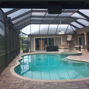 Large screened pool enclosure over a paver deck and freeform pool