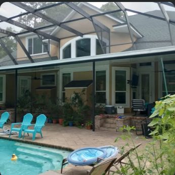 Pool enclosure over a patio with turquoise deck chairs and a two-storey home behind