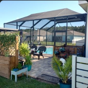 Screened patio enclosure over a pool with container planting and a privacy screen