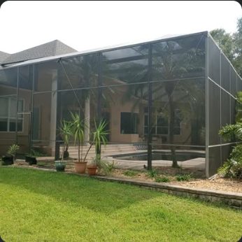 Tall screen enclosure on a wooded lot, framed bays visible against the tree line
